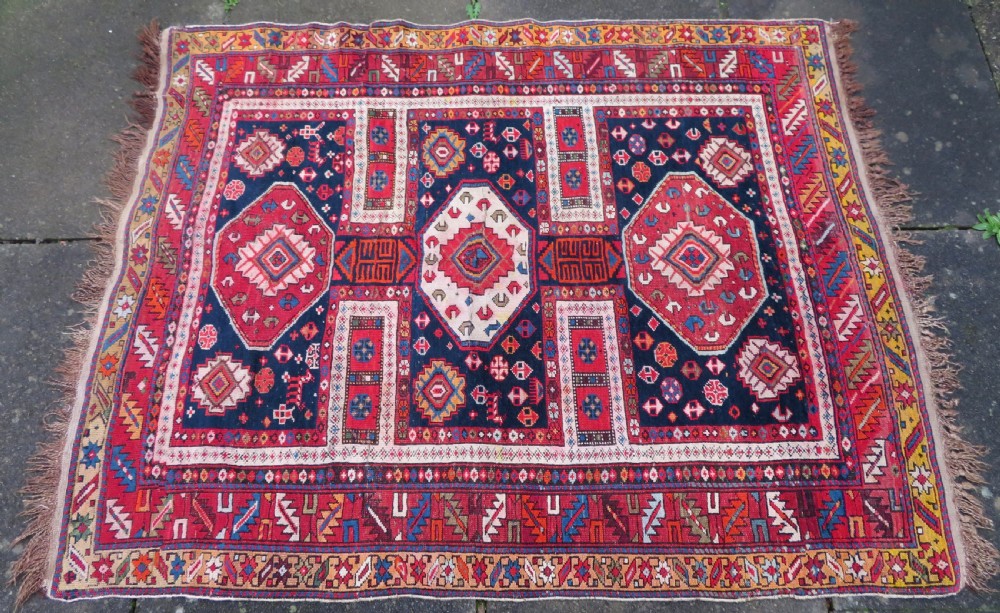 An antique late 19th-century Caucasian Kuba Konagkend wool rug featuring red geometric medallions set against a dark navy field with multi-coloured borders. View III