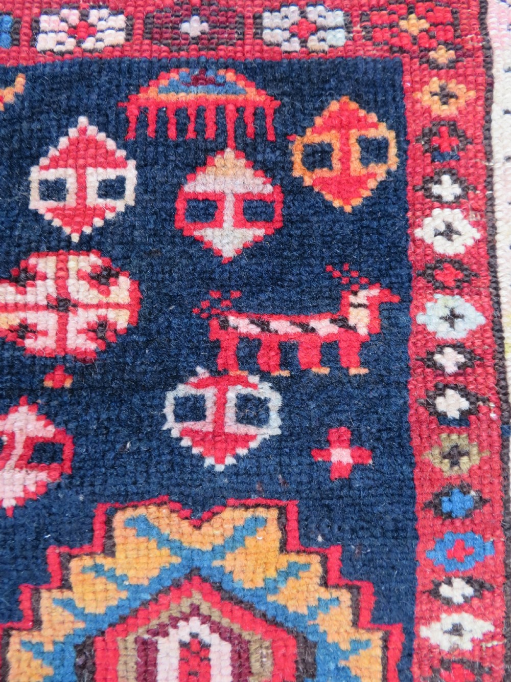An antique late 19th-century Caucasian Kuba Konagkend wool rug featuring red geometric medallions set against a dark navy field with multi-coloured borders. View VI