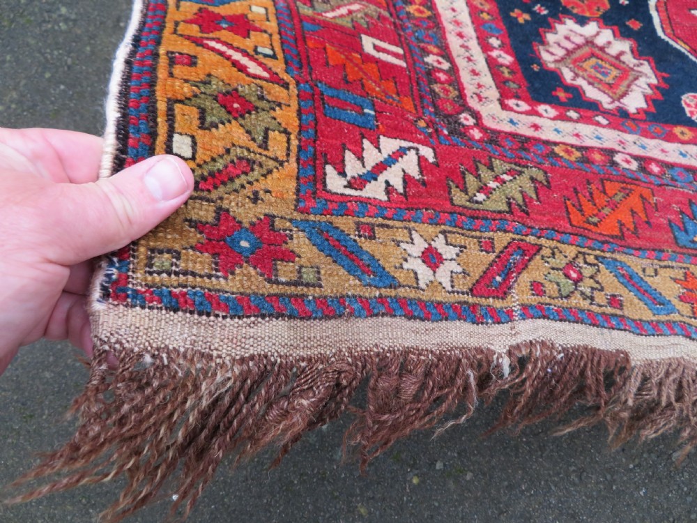 An antique late 19th-century Caucasian Kuba Konagkend wool rug featuring red geometric medallions set against a dark navy field with multi-coloured borders. View XI