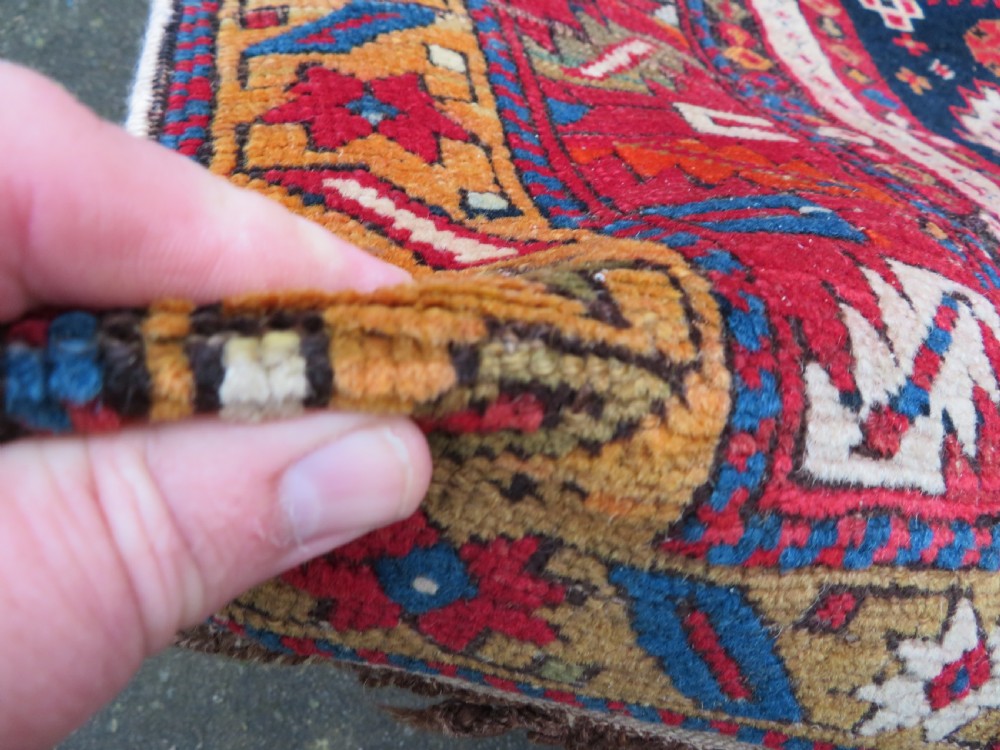 An antique late 19th-century Caucasian Kuba Konagkend wool rug featuring red geometric medallions set against a dark navy field with multi-coloured borders. View XII