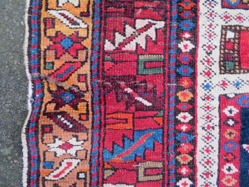 An antique late 19th-century Caucasian Kuba Konagkend wool rug featuring red geometric medallions set against a dark navy field with multi-coloured borders. View XIII