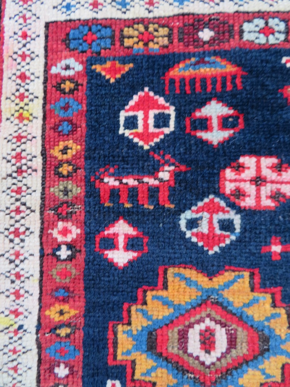 An antique late 19th-century Caucasian Kuba Konagkend wool rug featuring red geometric medallions set against a dark navy field with multi-coloured borders. View XIV