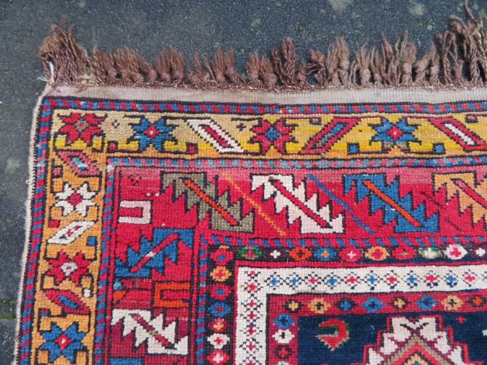 An antique late 19th-century Caucasian Kuba Konagkend wool rug featuring red geometric medallions set against a dark navy field with multi-coloured borders. View XVI