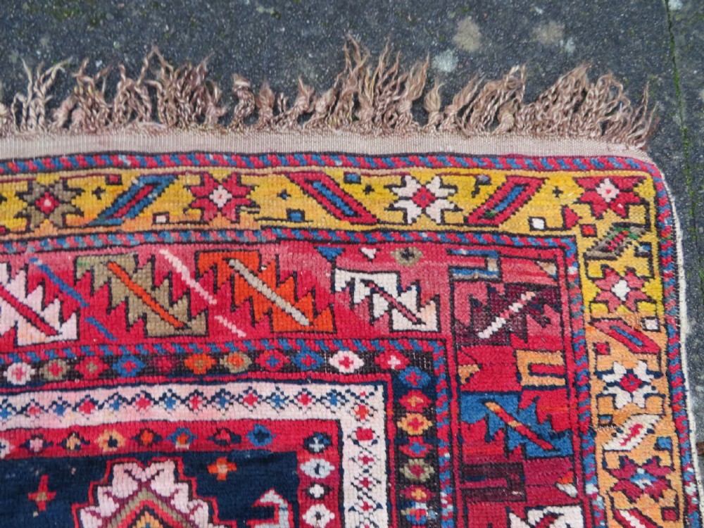 An antique late 19th-century Caucasian Kuba Konagkend wool rug featuring red geometric medallions set against a dark navy field with multi-coloured borders. View XVII