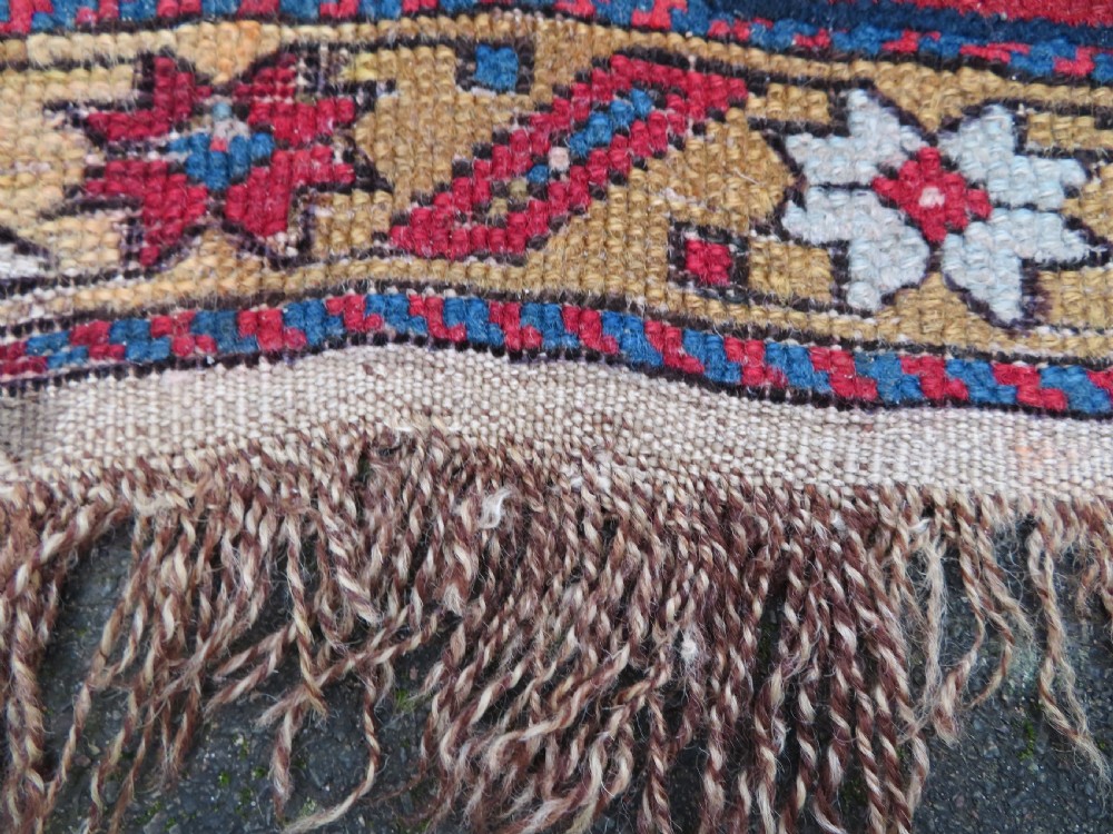An antique late 19th-century Caucasian Kuba Konagkend wool rug featuring red geometric medallions set against a dark navy field with multi-coloured borders. View XX