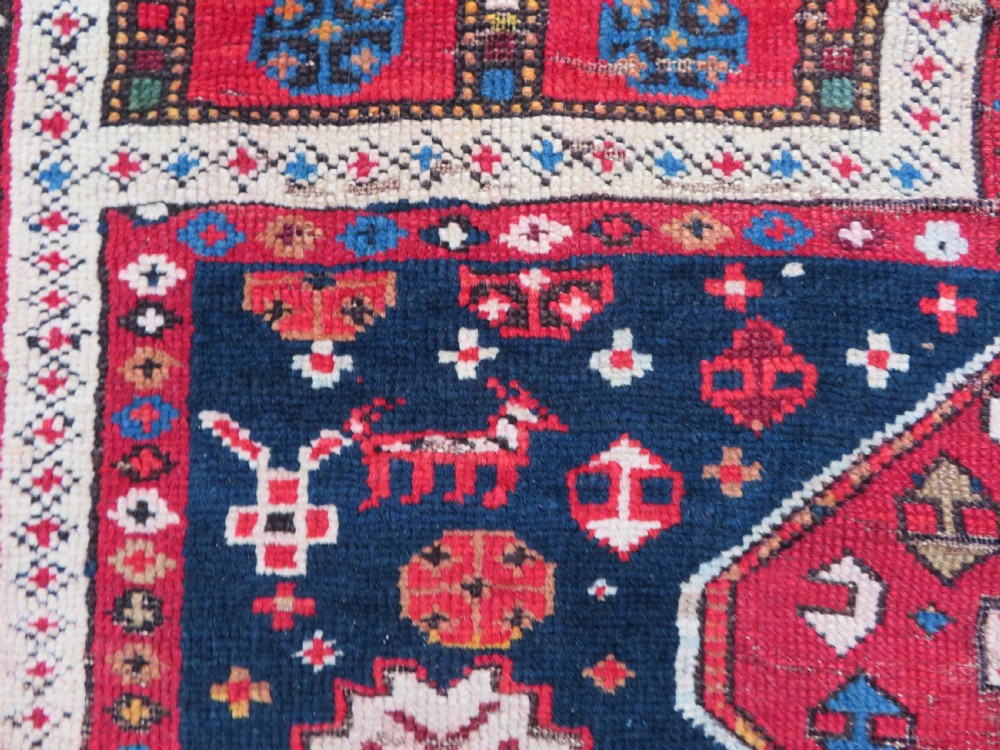 An antique late 19th-century Caucasian Kuba Konagkend wool rug featuring red geometric medallions set against a dark navy field with multi-coloured borders. View XXI