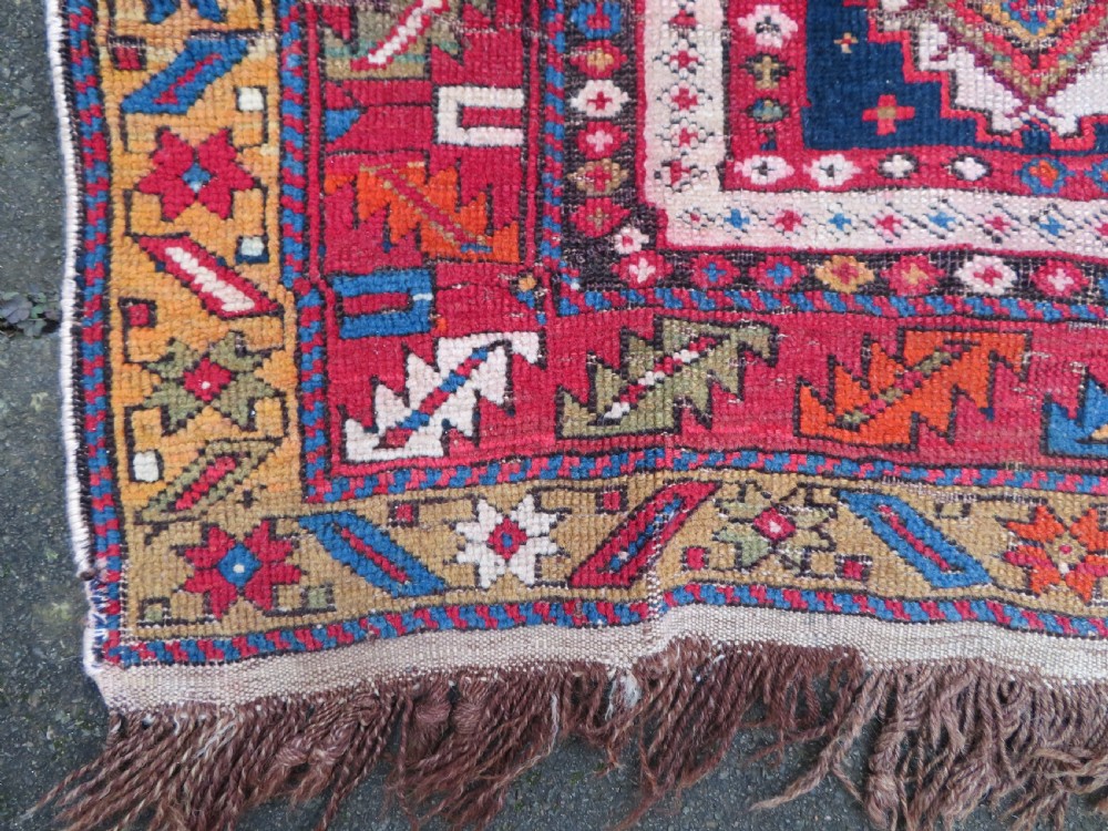 An antique late 19th-century Caucasian Kuba Konagkend wool rug featuring red geometric medallions set against a dark navy field with multi-coloured borders. View XXIII