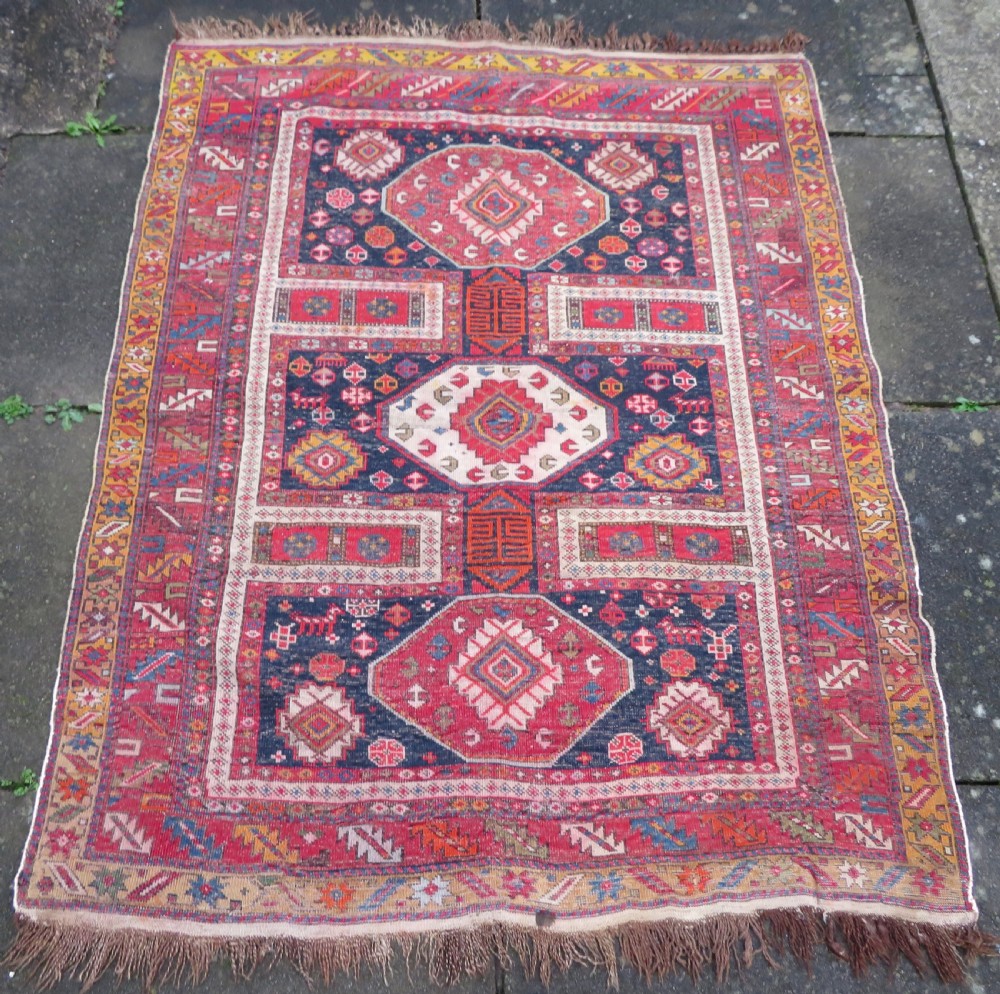 An antique late 19th-century Caucasian Kuba Konagkend wool rug featuring red geometric medallions set against a dark navy field with multi-coloured borders. View XXV