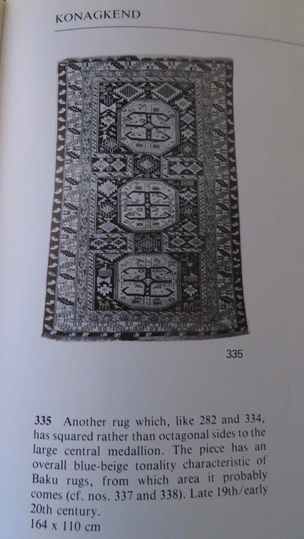 An antique late 19th-century Caucasian Kuba Konagkend wool rug featuring red geometric medallions set against a dark navy field with multi-coloured borders. View XXIX