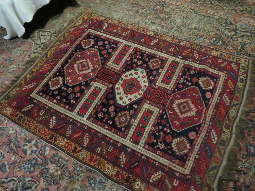 An antique late 19th-century Caucasian Kuba Konagkend wool rug featuring red geometric medallions set against a dark navy field with multi-coloured borders. View XXXI