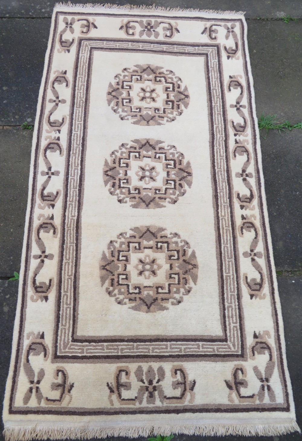 A rectangular hand-knotted wool rug runner featuring three central brown circular medallions on a cream background with a geometric border. View II