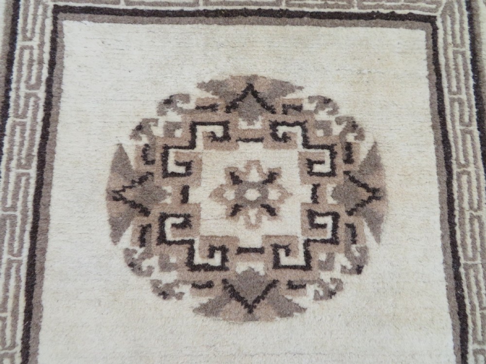 A rectangular hand-knotted wool rug runner featuring three central brown circular medallions on a cream background with a geometric border. View IV
