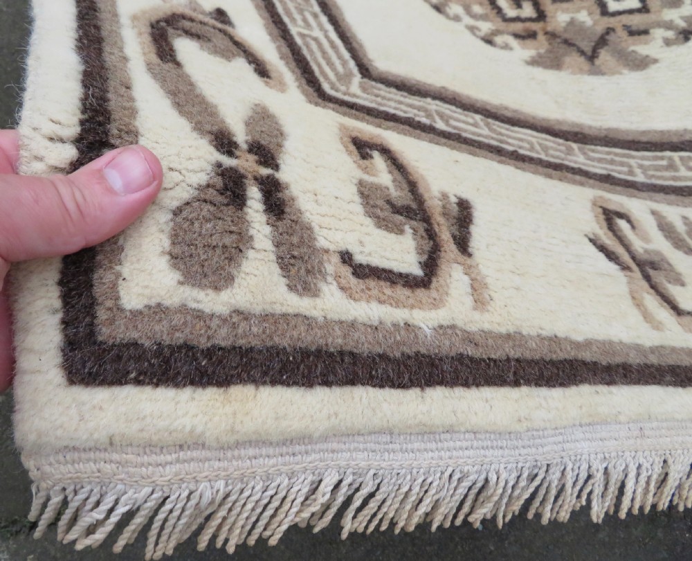 A rectangular hand-knotted wool rug runner featuring three central brown circular medallions on a cream background with a geometric border. View VII