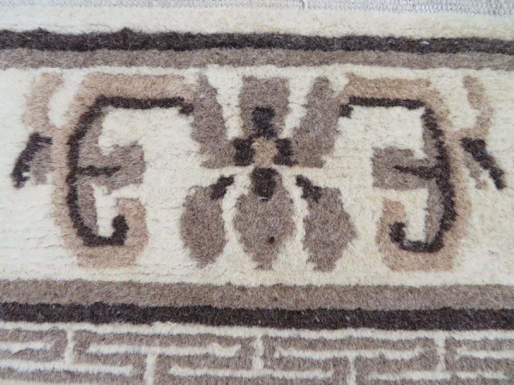 A rectangular hand-knotted wool rug runner featuring three central brown circular medallions on a cream background with a geometric border. View XI