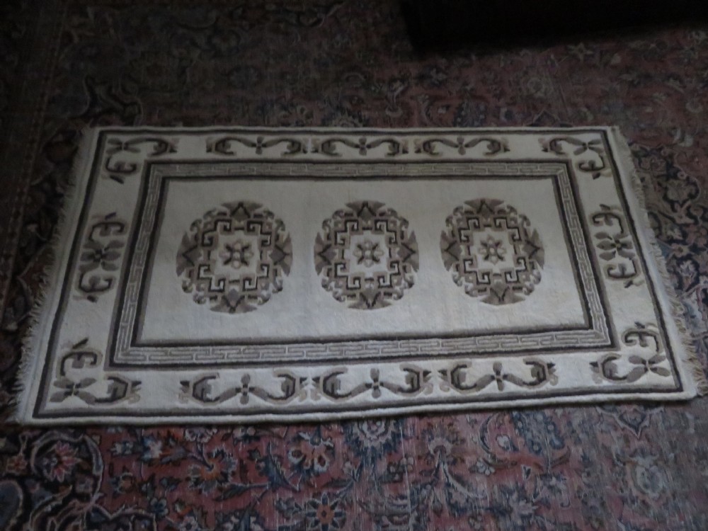 A rectangular hand-knotted wool rug runner featuring three central brown circular medallions on a cream background with a geometric border. View XX