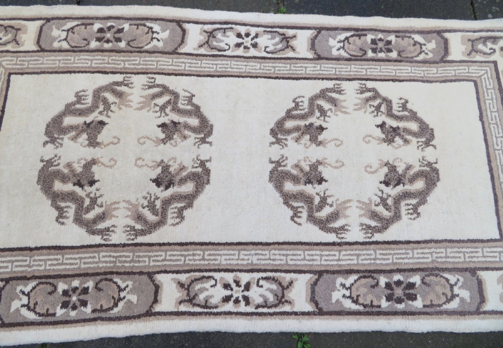 A rectangular hand-knotted cream wool rug featuring two central dragon medallions, a key meander border, and grey decorative motifs. View III