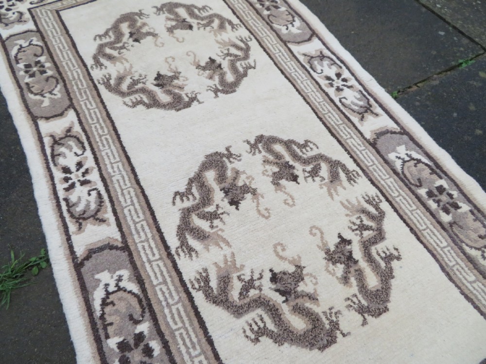 A rectangular hand-knotted cream wool rug featuring two central dragon medallions, a key meander border, and grey decorative motifs. View XI