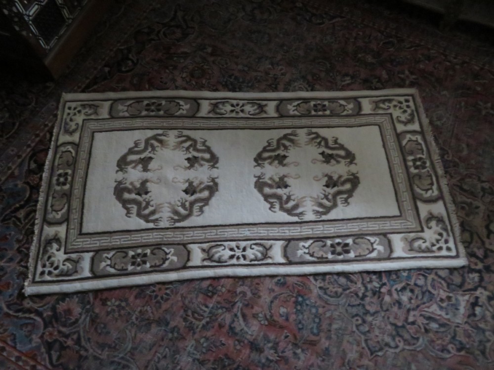 A rectangular hand-knotted cream wool rug featuring two central dragon medallions, a key meander border, and grey decorative motifs. View XVIII