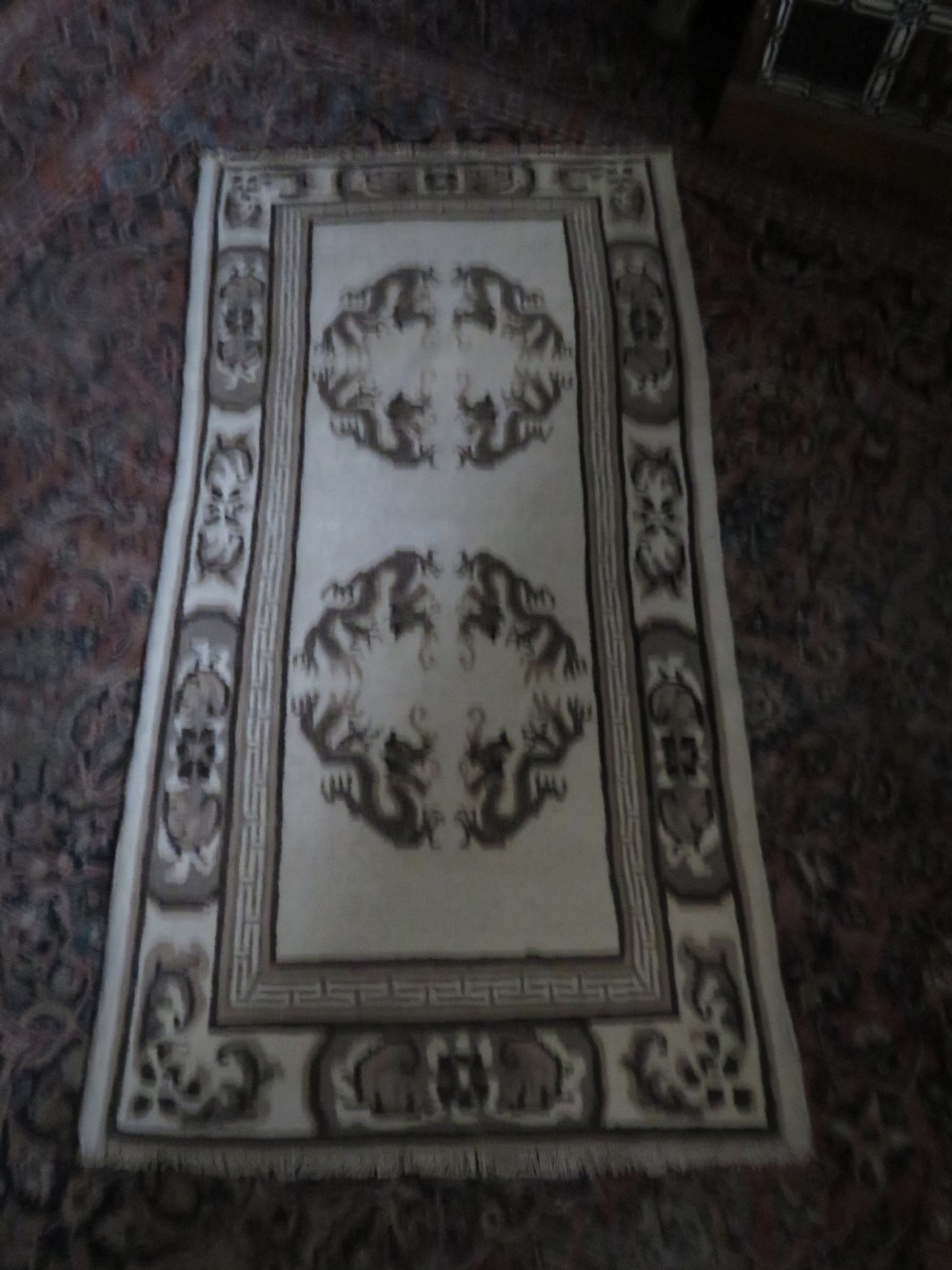 A rectangular hand-knotted cream wool rug featuring two central dragon medallions, a key meander border, and grey decorative motifs. View XIX