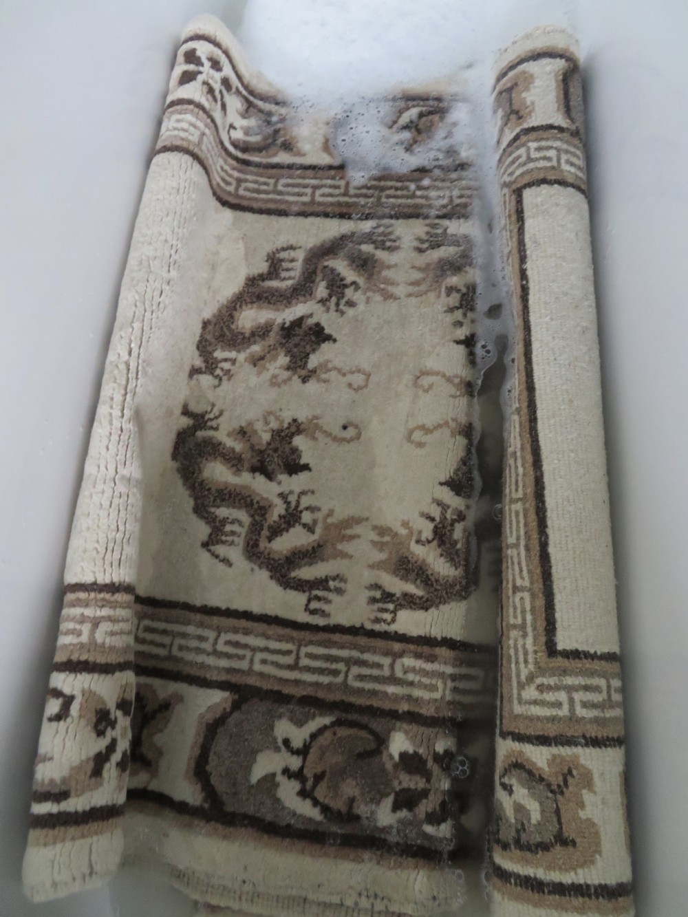 A rectangular hand-knotted cream wool rug featuring two central dragon medallions, a key meander border, and grey decorative motifs. View XX