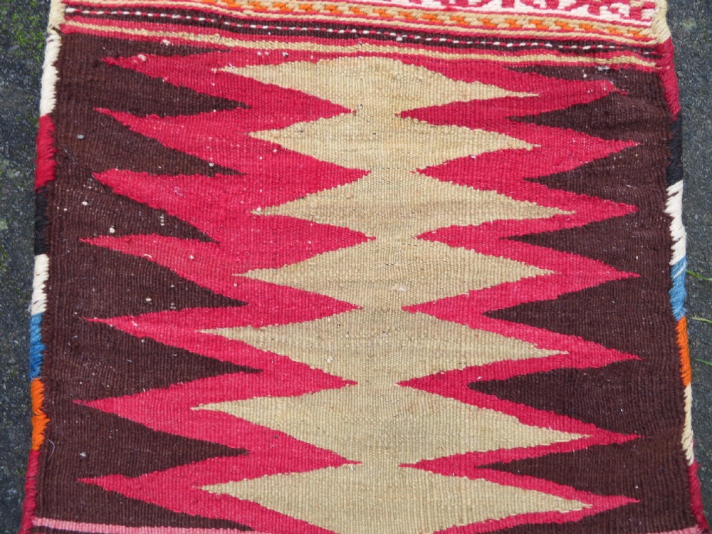 An antique woven wool Azerbaijan saddle bag displaying geometric serrated motifs in red, cream, and dark brown. View IV