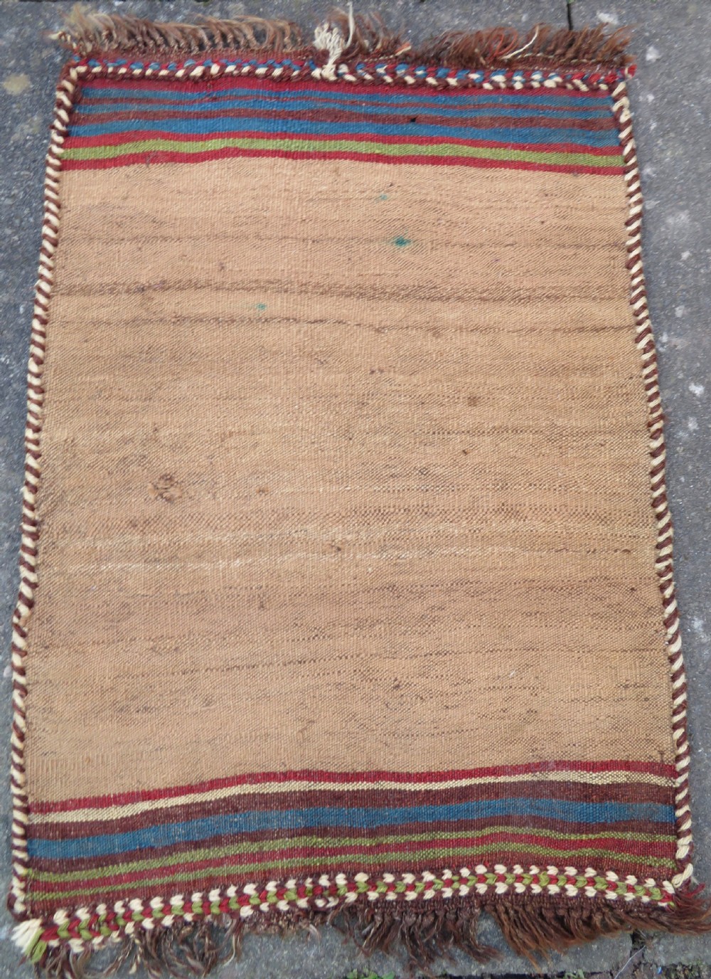 An antique flatweave rug featuring a central undyed tan wool field flanked by colourful horizontal striped end bands and braided fringe edges.