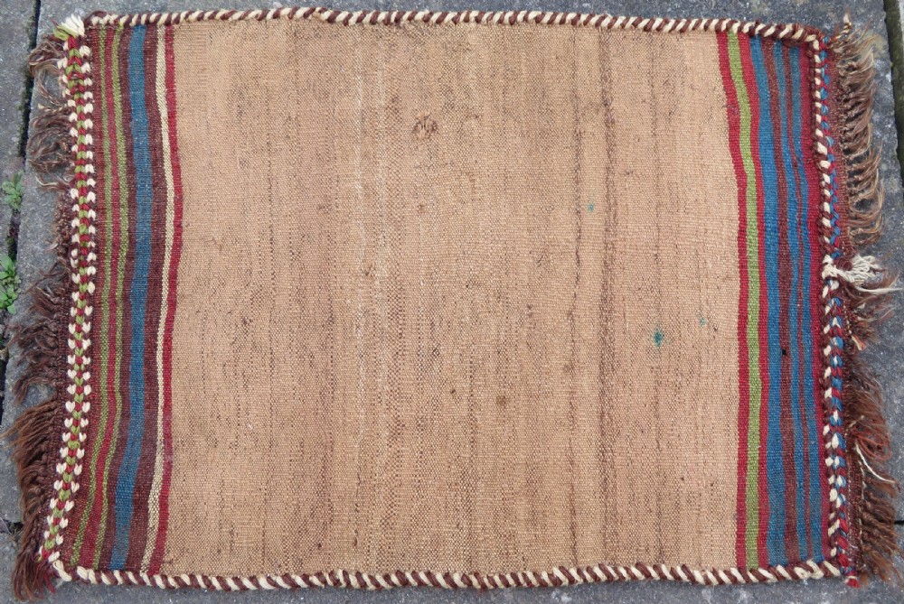 An antique flatweave rug featuring a central undyed tan wool field flanked by colourful horizontal striped end bands and braided fringe edges. View II