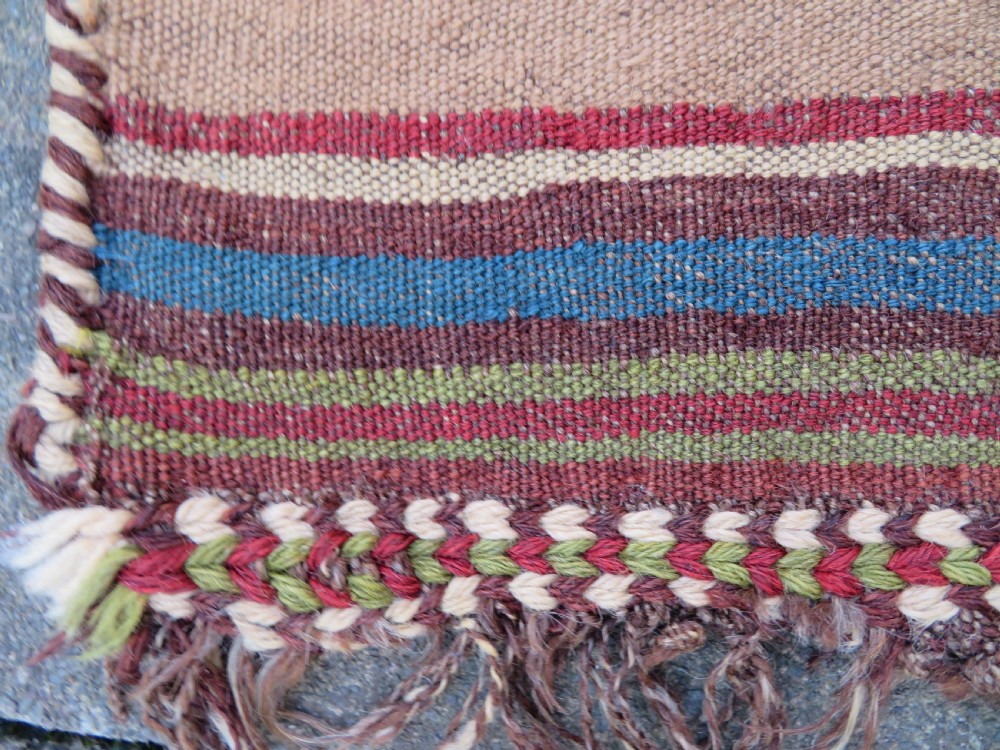 An antique flatweave rug featuring a central undyed tan wool field flanked by colourful horizontal striped end bands and braided fringe edges. View VIII
