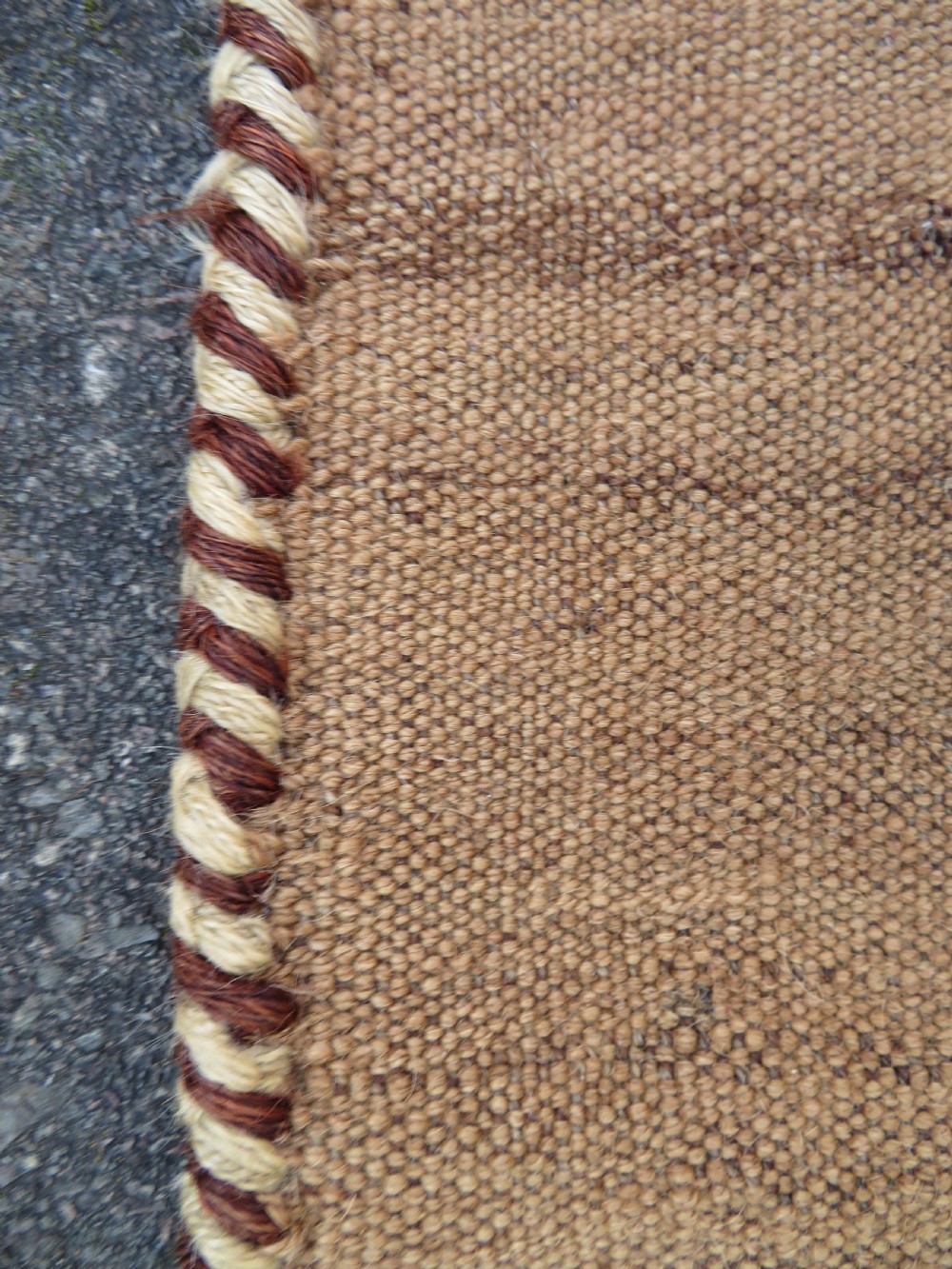 An antique flatweave rug featuring a central undyed tan wool field flanked by colourful horizontal striped end bands and braided fringe edges. View XII