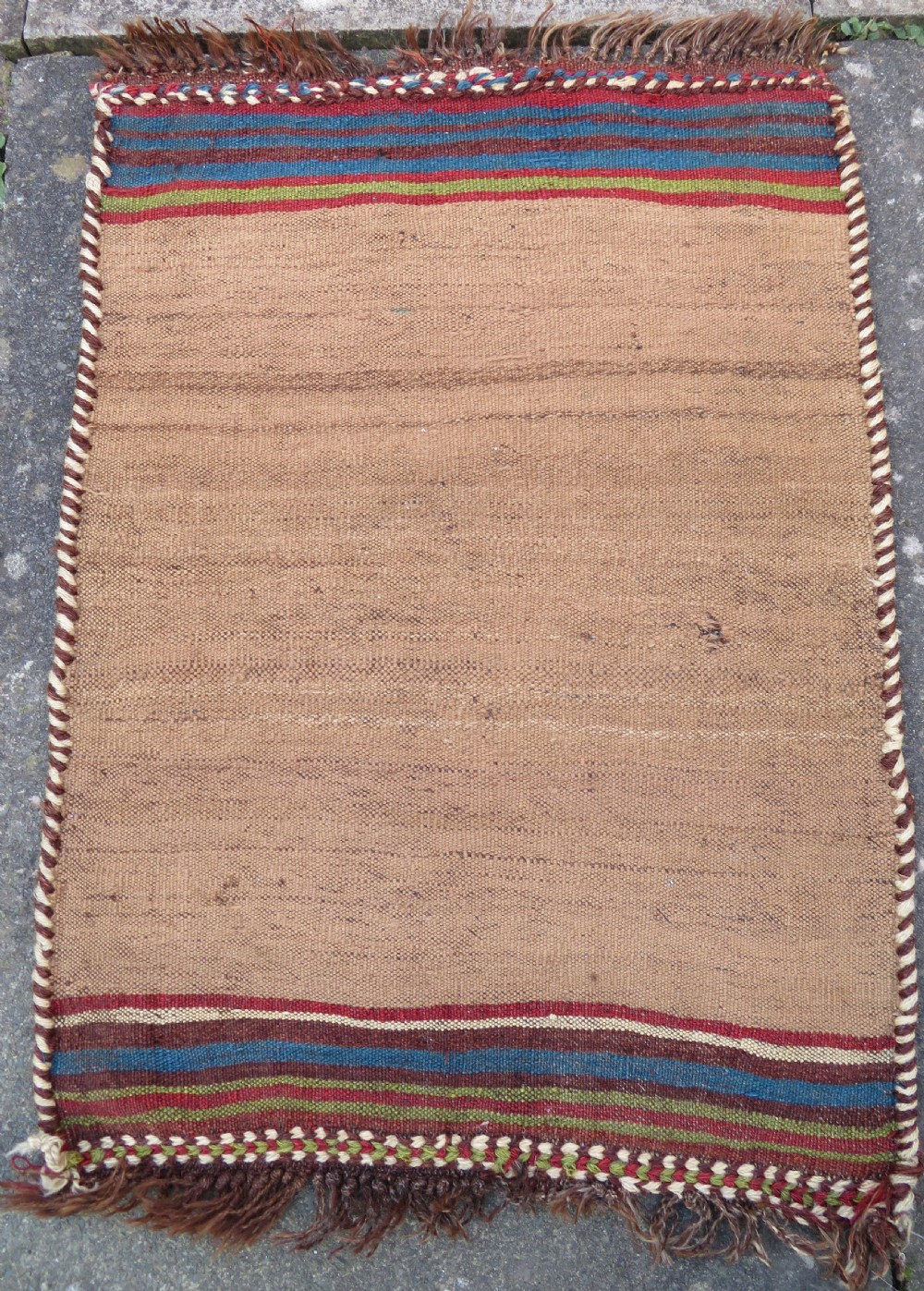 An antique flatweave rug featuring a central undyed tan wool field flanked by colourful horizontal striped end bands and braided fringe edges. View XIII