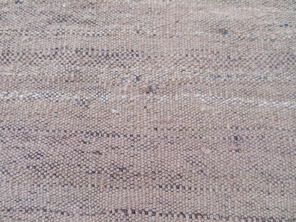 An antique flatweave rug featuring a central undyed tan wool field flanked by colourful horizontal striped end bands and braided fringe edges. View XVII
