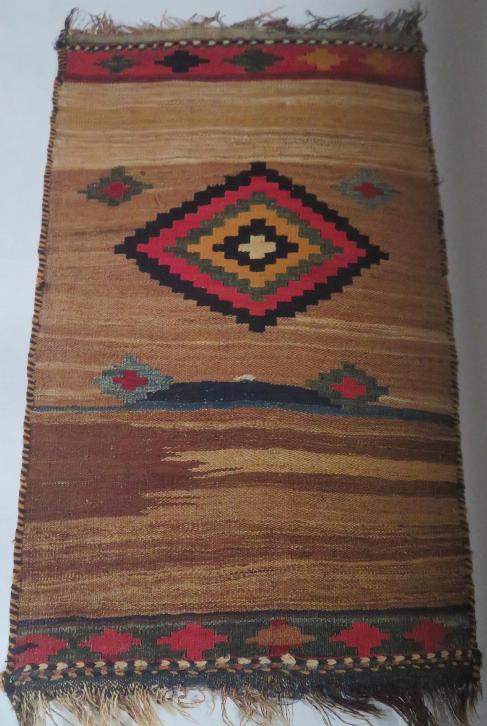 An antique flatweave rug featuring a central undyed tan wool field flanked by colourful horizontal striped end bands and braided fringe edges. View XX
