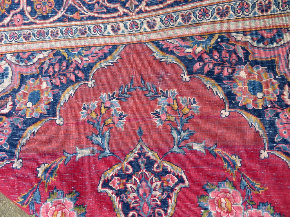 A hand-knotted Persian Kashan wool rug featuring a central navy and cream floral medallion on a rose pink field surrounded by floral spandrels and a navy border. View VI