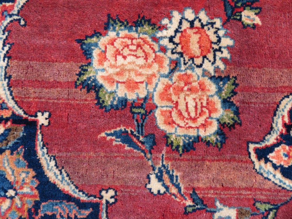A hand-knotted Persian Kashan wool rug featuring a central navy and cream floral medallion on a rose pink field surrounded by floral spandrels and a navy border. View VIII