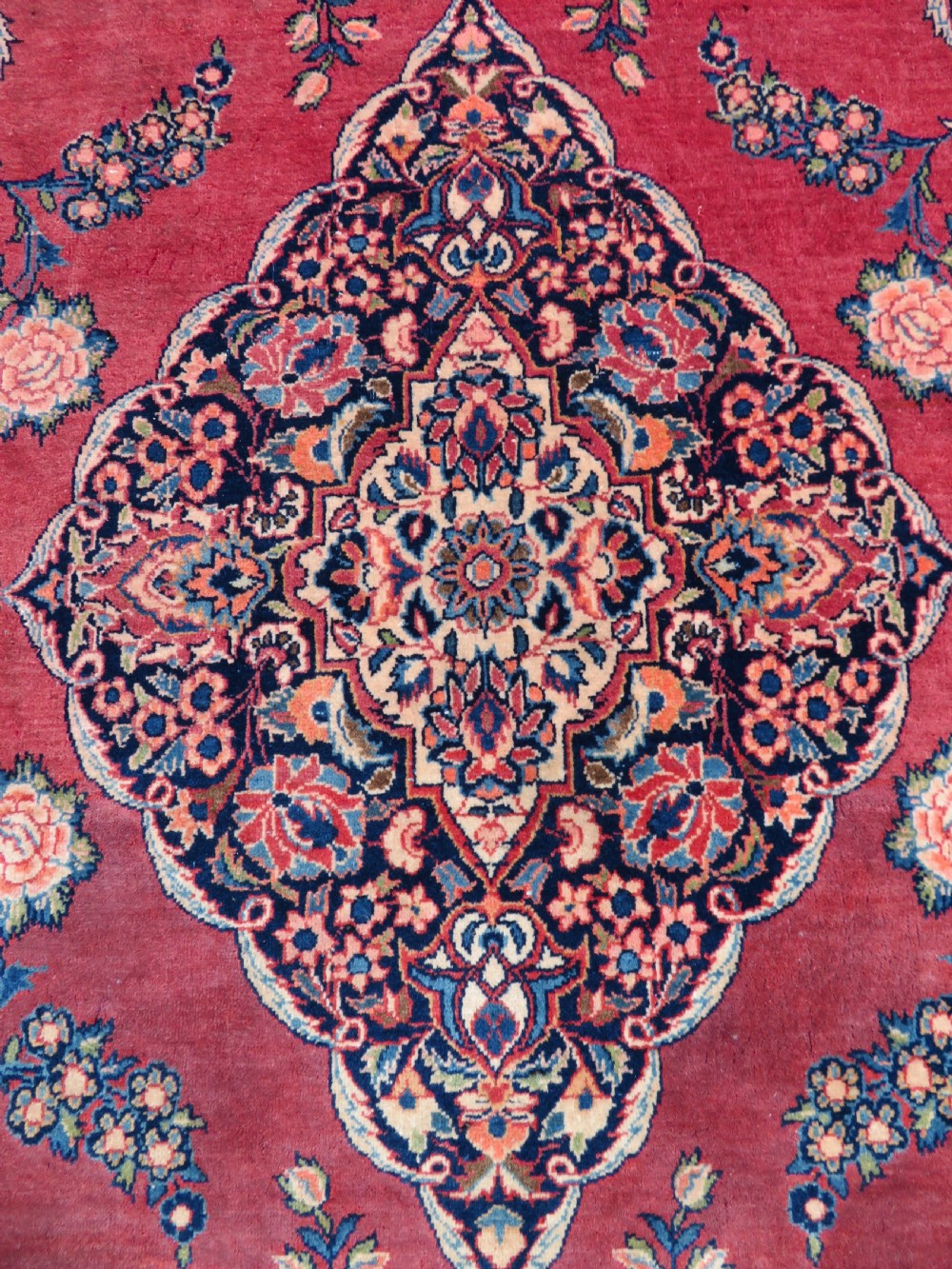 A hand-knotted Persian Kashan wool rug featuring a central navy and cream floral medallion on a rose pink field surrounded by floral spandrels and a navy border. View XI