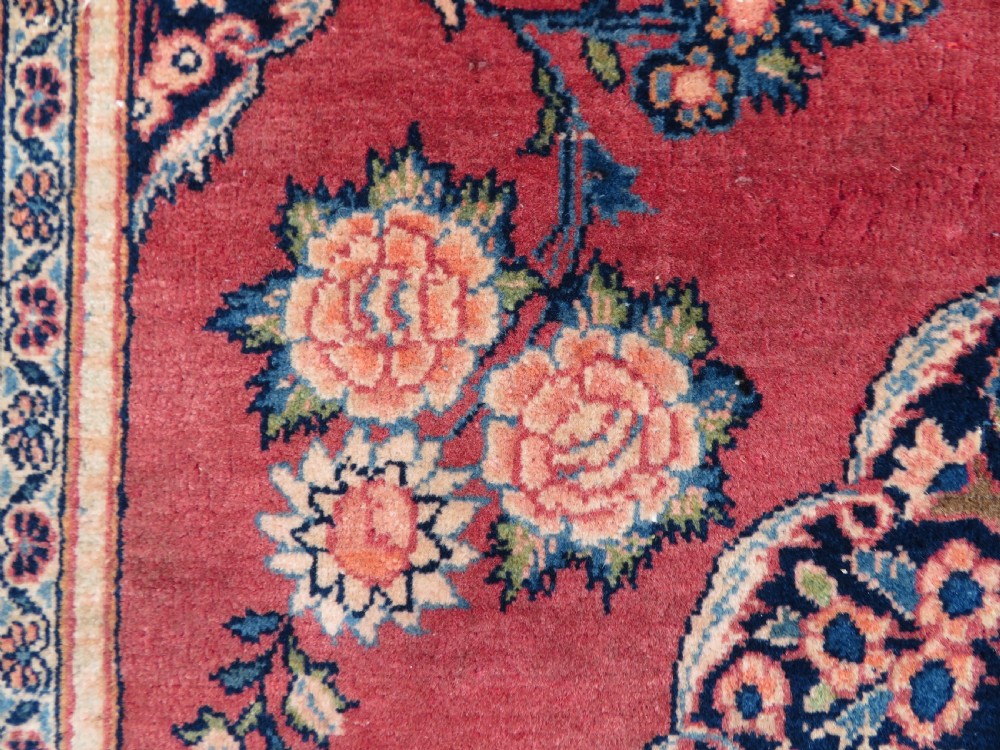 A hand-knotted Persian Kashan wool rug featuring a central navy and cream floral medallion on a rose pink field surrounded by floral spandrels and a navy border. View XIII