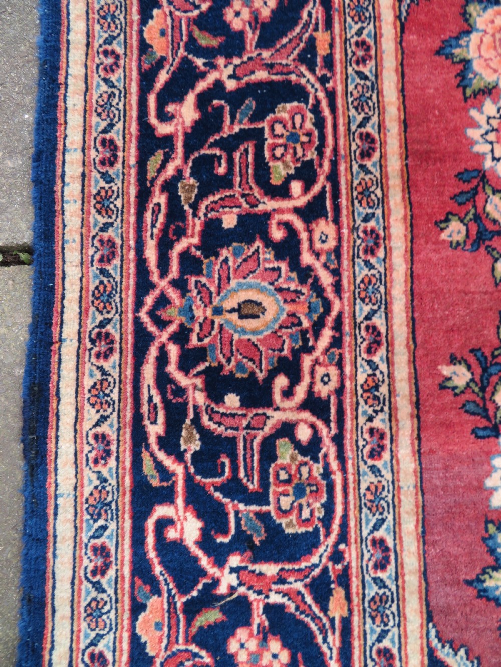 A hand-knotted Persian Kashan wool rug featuring a central navy and cream floral medallion on a rose pink field surrounded by floral spandrels and a navy border. View XIV