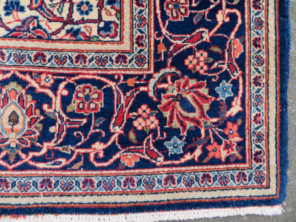 A hand-knotted Persian Kashan wool rug featuring a central navy and cream floral medallion on a rose pink field surrounded by floral spandrels and a navy border. View XV