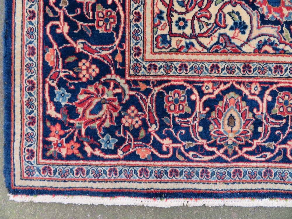 A hand-knotted Persian Kashan wool rug featuring a central navy and cream floral medallion on a rose pink field surrounded by floral spandrels and a navy border. View XVI