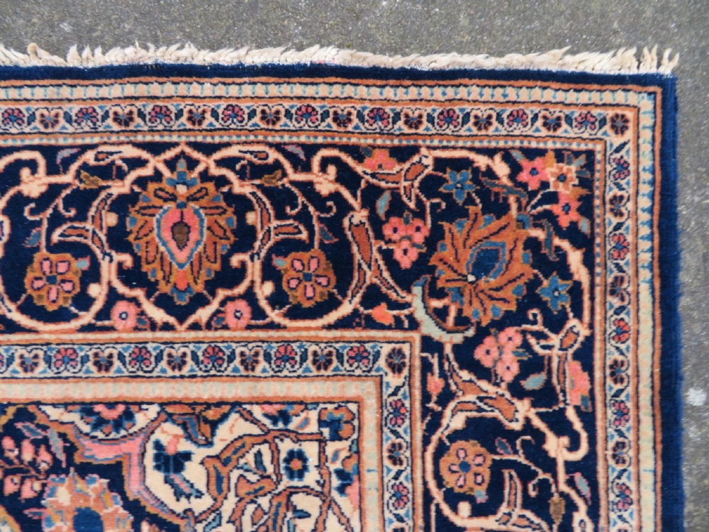 A hand-knotted Persian Kashan wool rug featuring a central navy and cream floral medallion on a rose pink field surrounded by floral spandrels and a navy border. View XVIII