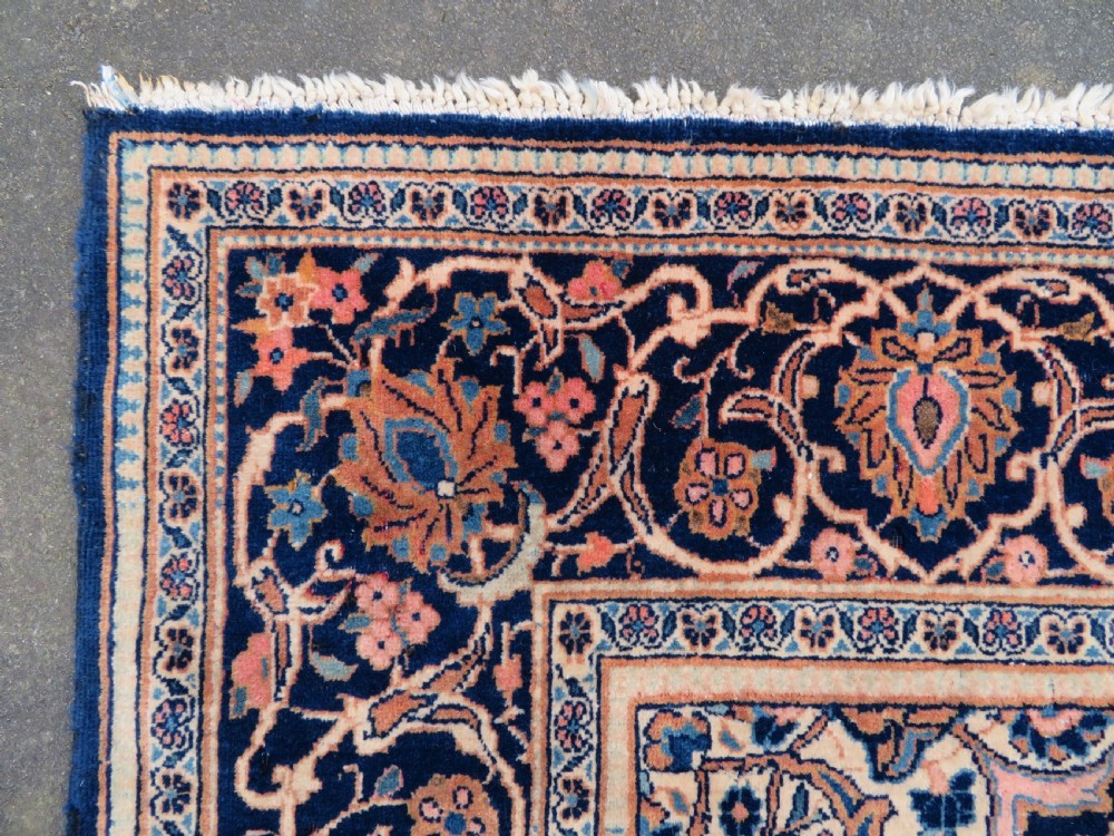 A hand-knotted Persian Kashan wool rug featuring a central navy and cream floral medallion on a rose pink field surrounded by floral spandrels and a navy border. View XIX