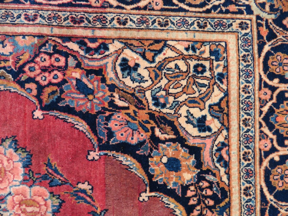A hand-knotted Persian Kashan wool rug featuring a central navy and cream floral medallion on a rose pink field surrounded by floral spandrels and a navy border. View XX