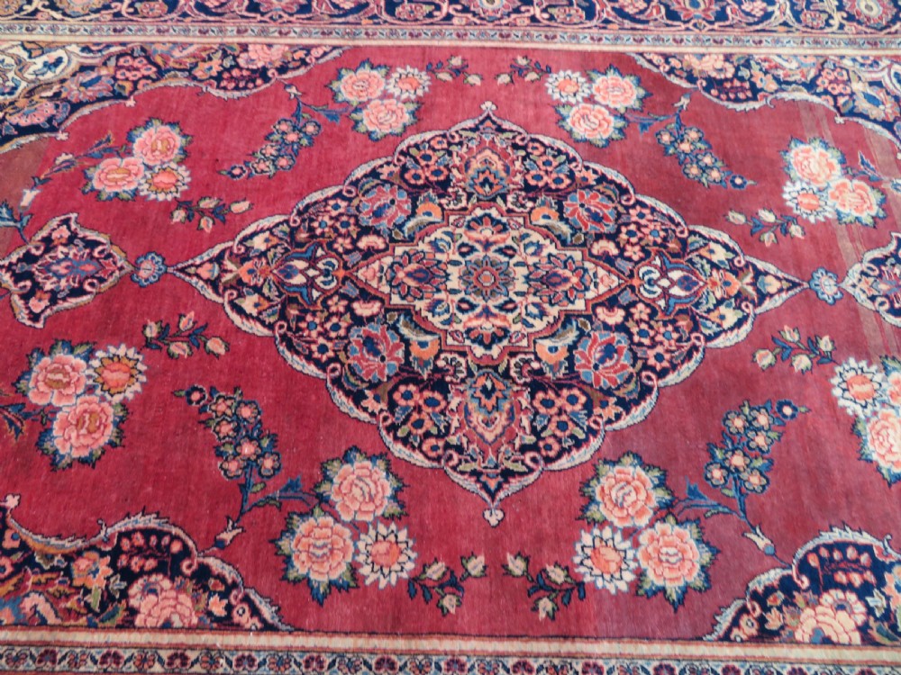 A hand-knotted Persian Kashan wool rug featuring a central navy and cream floral medallion on a rose pink field surrounded by floral spandrels and a navy border. View XXI
