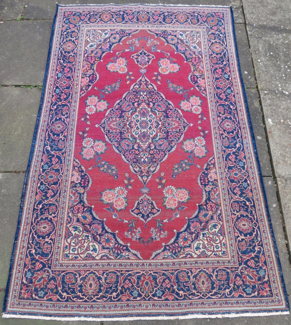 A hand-knotted Persian Kashan wool rug featuring a central navy and cream floral medallion on a rose pink field surrounded by floral spandrels and a navy border. View XXII
