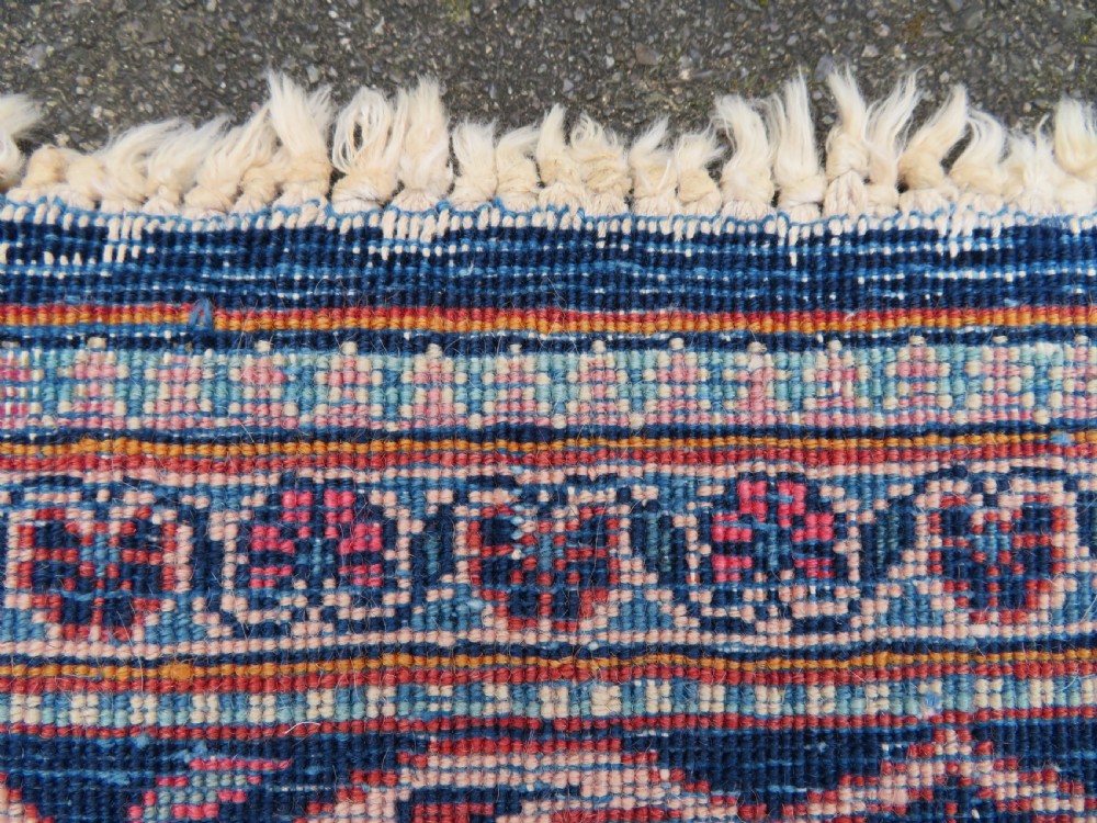 A hand-knotted Persian Kashan wool rug featuring a central navy and cream floral medallion on a rose pink field surrounded by floral spandrels and a navy border. View XXIV