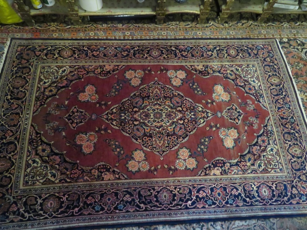 A hand-knotted Persian Kashan wool rug featuring a central navy and cream floral medallion on a rose pink field surrounded by floral spandrels and a navy border. View XXVII
