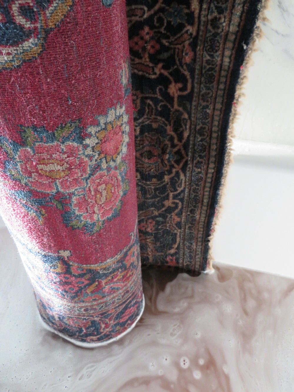 A hand-knotted Persian Kashan wool rug featuring a central navy and cream floral medallion on a rose pink field surrounded by floral spandrels and a navy border. View XXX