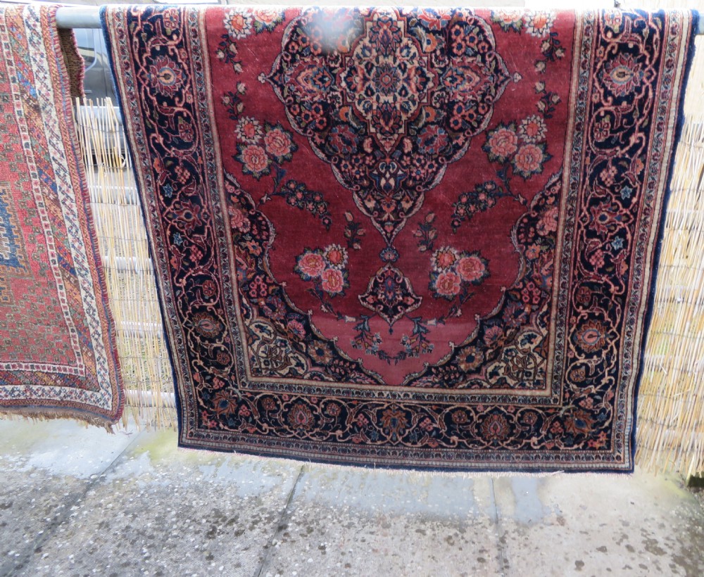A hand-knotted Persian Kashan wool rug featuring a central navy and cream floral medallion on a rose pink field surrounded by floral spandrels and a navy border. View XXXI