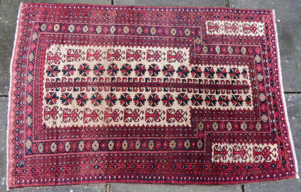 An antique hand-knotted Baluch wool rug featuring a central tree of life design on a cream field surrounded by red and navy geometric borders. View III