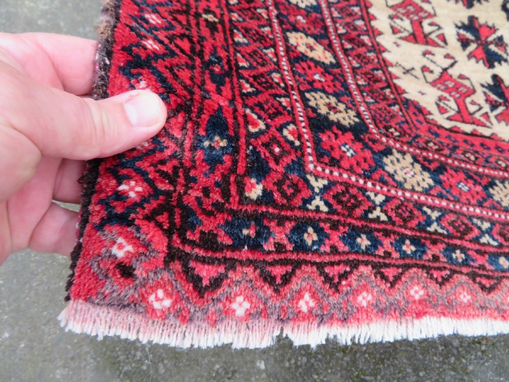 An antique hand-knotted Baluch wool rug featuring a central tree of life design on a cream field surrounded by red and navy geometric borders. View IX